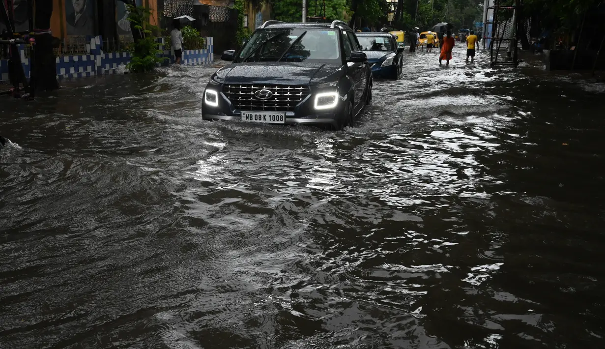 Sejumlah mobil melewati jalan yang tergenang air di tengah hujan lebat di Kolkata (20/9/2021). Hujan dilaporkan dipicu oleh sirkulasi siklon yang terbentuk di atas Teluk Benggala. (AFP/Dibyangshu Sarkar)