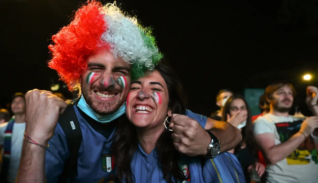 Reaksi fans setelah timnas Italia mencetak gol kedua saat mereka menonton di layar raksasa dari zona penggemar resmi di Piazza del Popolo di Roma pada laga pertama grup A Euro 2020 /2021, Jumat (11/6/2021). Timnas Italia berhasil menang 3-0 atas Turki. (Vincenzo PINTO / AFP)
