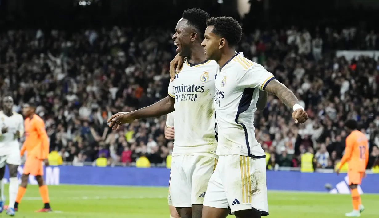 Pemain Real Madrid, Vinicius Junior dan Rodrygo melakukan selebrasi setelah mencetak gol ke gawang Valencia pada laga Liga Spanyol di Stadion Santiago Bernabeu, Sabtu (11/11/2023). Kedua pemain asal Brasil ini kompak mencetak dua gol. (AP Photo/Jose Breton)
