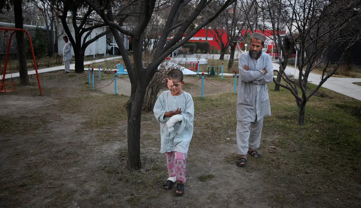 Ismatullah mengikuti putranya Eimal (9) yang kehilangan mata kanan dan beberapa jari tangannya dalam ledakan ranjau darat berjalan di kompleks darurat Pusat Bedah Darurat untuk Korban Perang Sipil, Kabul, Afghanistan, Kamis (12/12/2019 ). (AP Photo/Altaf Qadri)