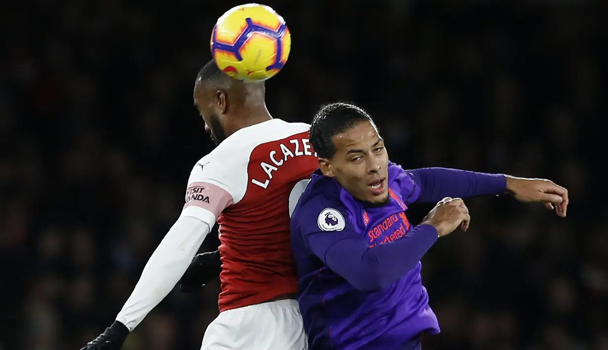 Striker Arsenal, Alexandre Lacazette, duel udara dengan bek Liverpool, Virgil Van Dijk, pada laga Premier League di Stadion Emirates, London, Minggu (3/11). Kedua klub bermain imbang 1-1. (AFP/Ian Kington)