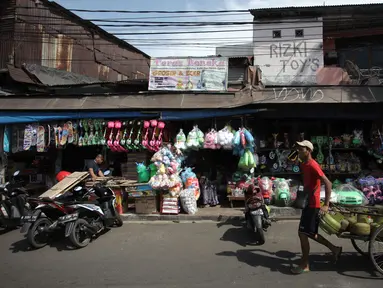 Pedagang gas melintasi kios mainan di Pasar Gembrong, Jakarta, Selasa (9/1). Maret mendatang, Pemprov DKI berencana menggusur kawasan Pasar Gembrong untuk pembangunan tol Becakayu, yang berakhir di Kampung Melayu, Jatinegara. (Liputan6.com/Arya Manggala)