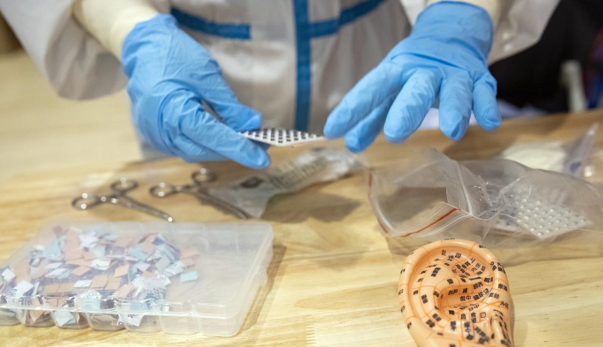 Perawat Tu Li bersiap merawat pasien menggunakan terapi pengobatan tradisional China (traditional Chinese medicine/TCM) di rumah sakit sementara di Wuhan, China (25/2/2020). Rumah sakit sementara yang pertama menerapkan metode perawatan dan manajemen rumah sakit TCM di China. (Xinhua/Shen Bohan)