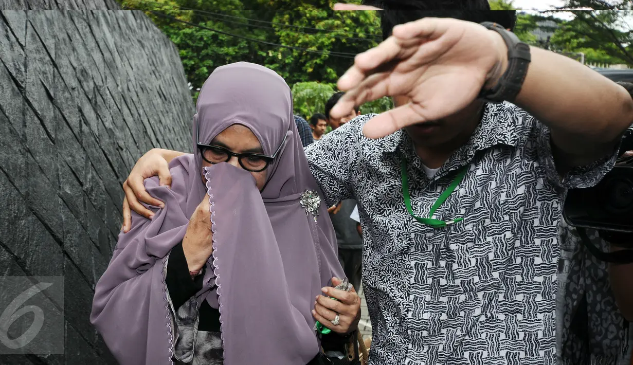 Istri Hakim MK Patrialis Akbar, Sufriyeni (kiri) menutup wajah saat menuju ruang tahanan KPK, Jakarta, Senin (30/1). Patrialis Akbar menjadi tersangka dugaan penerima suap uji materi UU peternakan dan Kesehatan Hewan. (Liputan6.com/Helmi Fithriansyah)