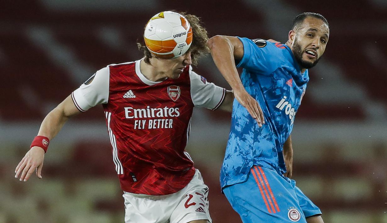 Bek Arsenal, David Luiz (kiri) berduel udara dengan striker Olympiakos, Youssef El-Arabi dalam laga leg kedua babak 16 besar Liga Europa 2020/2021 di Emirates Stadium, London, Kamis (18/3/2021). Arsenal kalah 0-1 dari Olympiakos. (AP/Matt Dunham)