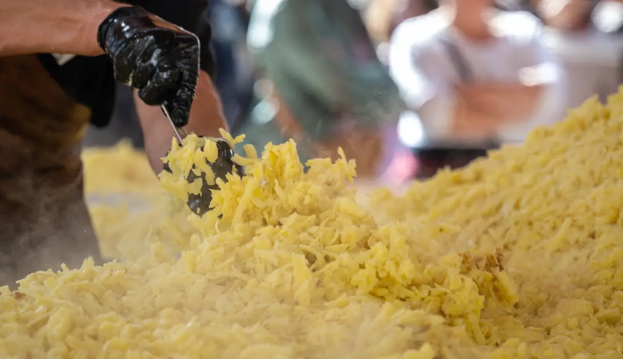 Koki memasak rosti dalam upaya memecahkan rekor dunia saat acara yang menandai peringatan 125 tahun Serikat Petani Swiss (SBV) di Bern, Swiss pada 19 September 2022. Sebagian dari rosti itu kemudian dibagikan kepada warga yang menonton acara itu. (Fabrice COFFRINI / AFP)
