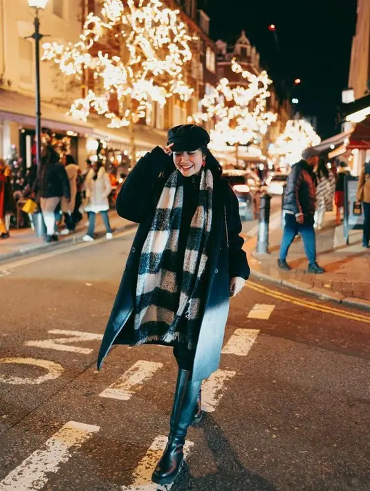 Suka gaya monokromatik? Padukan long coat dengan knee-high boots dan syal serba hitam.