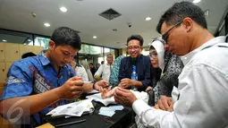 Salah satu petugas KPK melakukan pendataan keluarga tahanan yang akan membesuk ke ruang tahanan KPK Jakarta, Jumat (17/7/2015). Tampak, keluarga Suryadharma Ali saat melakukan pendaftaran kunjungan di hari pertama Lebaran. (Liputan6.com/Yoppy Renato)