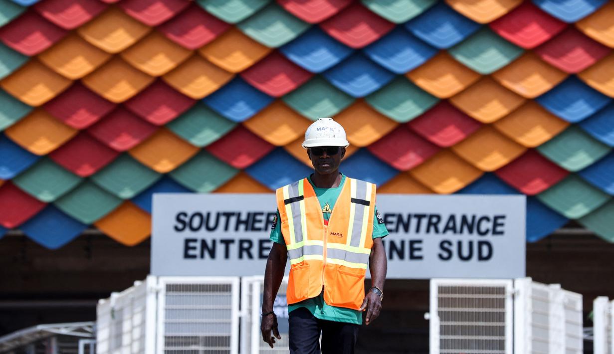 Seorang pekerja berjalan keluar dari Stadion Olembe yang terletak di Yaounde, pada 7 Januari 2022. Stadion yang berkapasitas 60.000 penonton tersebut rencananya akan digunakan untuk venue pembukaan Piala Africa 2021. (AFP/Kenzo Tribouillard).