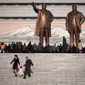 Sebuah keluarga berjalan menuruni tangga setelah memberikan penghormatan di depan dua patung pemimpin Korea Utara sebelumnya (AFP)