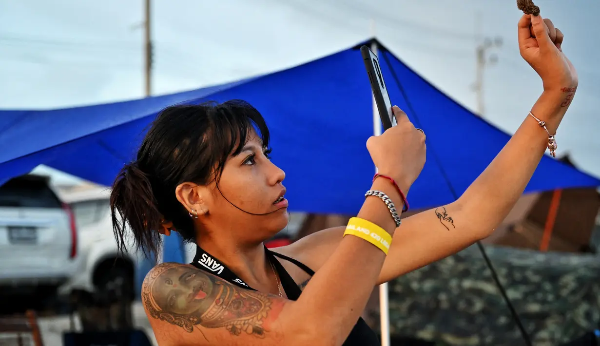 Seorang wanita mengambil gambar kuncup untuk merayakan legalisasi ganja di "Thailand: 420 Legalaew!" festival akhir pekan yang diselenggarakan oleh Highland di provinsi Nakhon Pathom pada 11 Juni 2022. (AFP/Lillian Suwanrumpha)