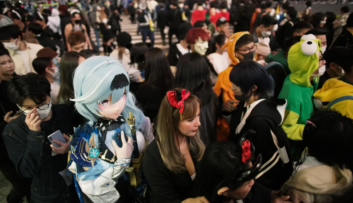 Orang-orang dengan kostum berjalan menyeberangi persimpangan jalan yang terkenal saat perayaan Halloween di distrik hiburan Shibuya, Tokyo, Jepang, 31 Oktober 2022. (AP Photo/Hiro Komae)