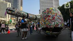 Aktivis lingkungan dari komunitas Aksi Muda Jaga Iklim berpawai dengan membawa replika ikan paus dan ular raksasa yang terbuat dari sampah plastik di kawasan Bundaran Hotel Indonesia, Jakarta, Minggu (27/10/2024). (Liputan6.com/Angga Yuniar)