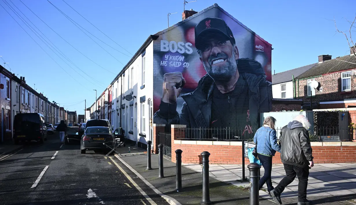 Pejalan kaki berjalan melewati mural karya seniman Hugh Whitaker dari MurWalls bergambar manajer Liverpool, Jurgen Klopp di dekat Anfield, Liverpool, barat laut Inggris, pada 26 Januari 2024. (Paul ELLIS/AFP)