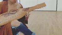 Atiqah Hasiolan saat memainkan sape'. (dok. instagram.com/atiqahhasiolan/https://www.instagram.com/p/B2sUHAgBPFh/Novi Thedora)