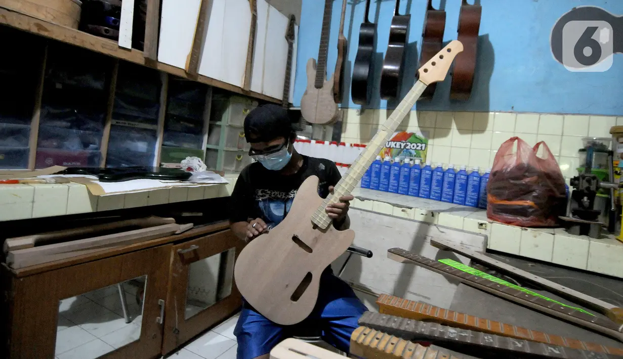 Pekerja menyelesaikan pembuatan gitar listrik Syukey Instrumen di kawasan Ciputat Timur, Tangerang Selatan, Banten, Selasa (26/10/2021). Dalam sebulan, pekerja mampu memproduksi 3 - 4 gitar listrik dengan harga Rp 3,5 juta hingga Rp 45 juta. (merdeka.com/Arie Basuki)