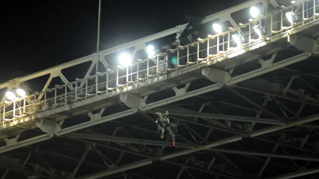 Seorang penerjun TNI tergantung saat tersangkut dalam penerjunan di atap Stadion GBK Jakarta, Minggu (24/1/2016). Aksi terjun payung menjadi rangkaian peringatan 100 tahun dan final Piala Jenderal Sudirman. (Liputan6.com/Helmi Fithriansyah)