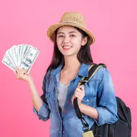 Seorang perempuan dengan pakaian berlibur sedang memegang sejumlah uang (Foto Dok: Freepik/jcomp).