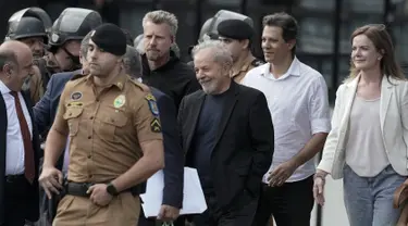 Mantan Presiden Brasil Luiz Inacio Lula da Silva (tengah) tersenyum ketika berjalan keluar dari markas Polisi Federal setelah dipenjara atas tuduhan korupsi di Curitiba, Brasil, (8/11/2019). Luiz Inácio Lula da Silva telah dibebaskan setelah lebih dari 18 bulan dipenjara. (AP Photo/Leo Correa)