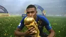 Striker Prancis, Kylian Mbappe, mencium trofi Piala Dunia usai menjadi juara Piala Dunia 2018 di Luzhniki Stadium, Moscow, (15/6/2018). Prancis menang 4-2 atas Krosia. (AFP/Franck Fife)