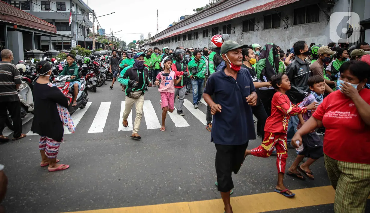 Warga dan pengemudi ojek online mengantre nasi kotak serta masker dari TNI di Markas Komando Gabungan Wilayah I, Jakarta, Selasa (21/4/2020). Dalam rangka Hari Kartini, TNI membagikan makanan dan masker kepada masyarakat. (Liputan6.com/Faizal Fanani)