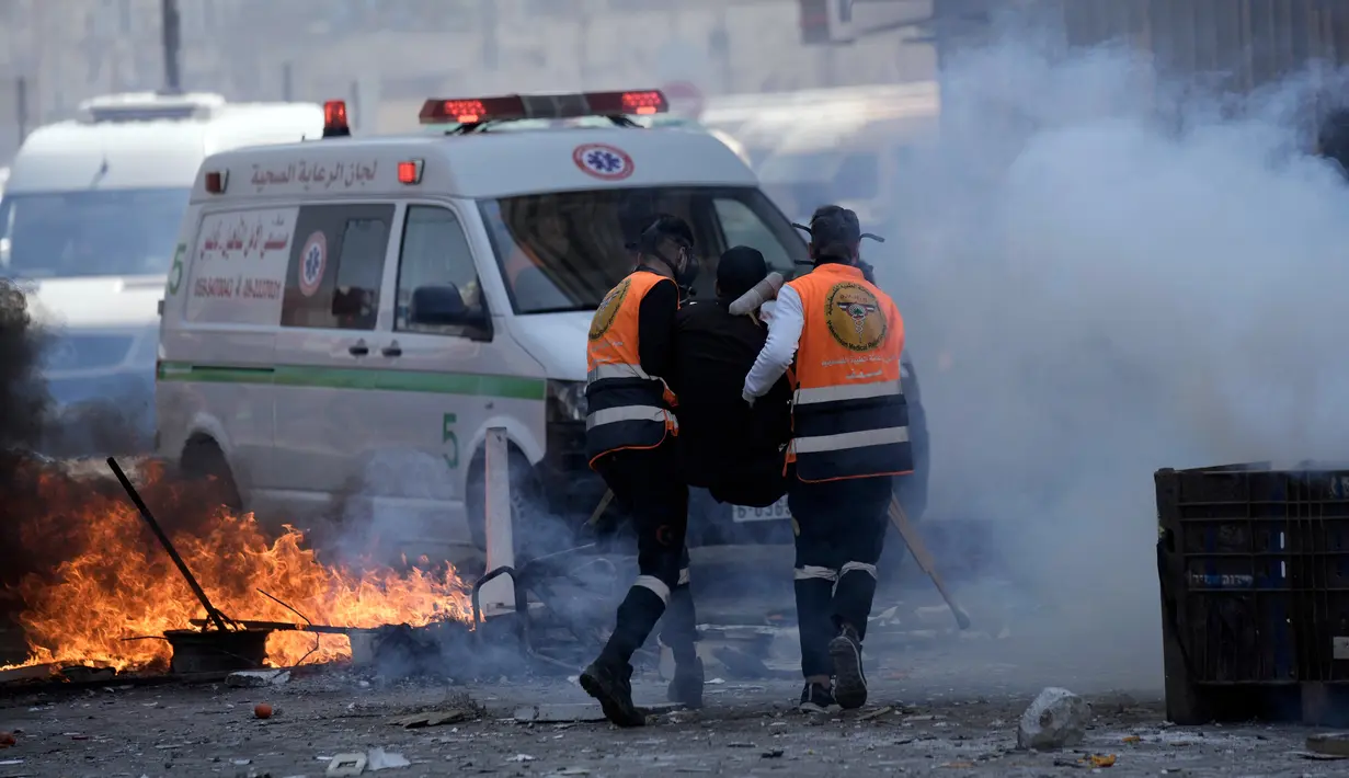 Petugas medis berlari melewati gas air mata saat mengevakuasi seorang warga Palestina yang terluka dalam bentrokan dengan pasukan Israel di Kota Nablus, Tepi Barat, 22 Februari 2023. Kelompok bersenjata Lions Den mengatakan dalam sebuah pernyataan bahwa mereka terlibat dalam bentrokan dengan pasukan Israel selama serangan itu, bersama dengan Brigade Balata yang baru-baru ini diumumkan. (AP Photo/Majdi Mohammed)