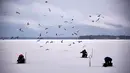 Sejumlah pria dikelilingi kawanan burung camar ketika memancing di tengah laut Bothnia yang membeku di Vaasa, Finlandia, Rabu (27/12). Selain suhu ekstrem, pemancing dapat melakukan aksinya di tengah laut dengan berjalan kaki. (OLIVIER MORIN / AFP)