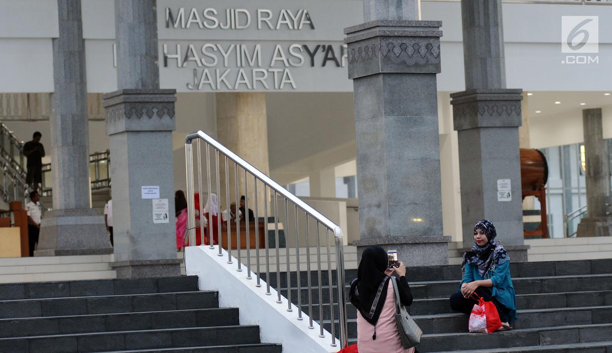 Warga berfoto di sekitar halaman Masjid Raya KH Hasyim Asyari Jakarta, Senin (29/5). Di hari ketiga Ramadan belum nampak kegiatan menonjol yang diadakan saat menanti datangnya waktu berbuka puasa. (Liputan6.com/Helmi Fithriansyah)