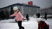 Anak-anak perempuan bermain salju di Kim Il Sung Square, Pyongyang, Korea Utara, Minggu (16/12). Korea Utara saat ini mulai memasuki musim dingin. (AP Photo/Dita Alangkara)