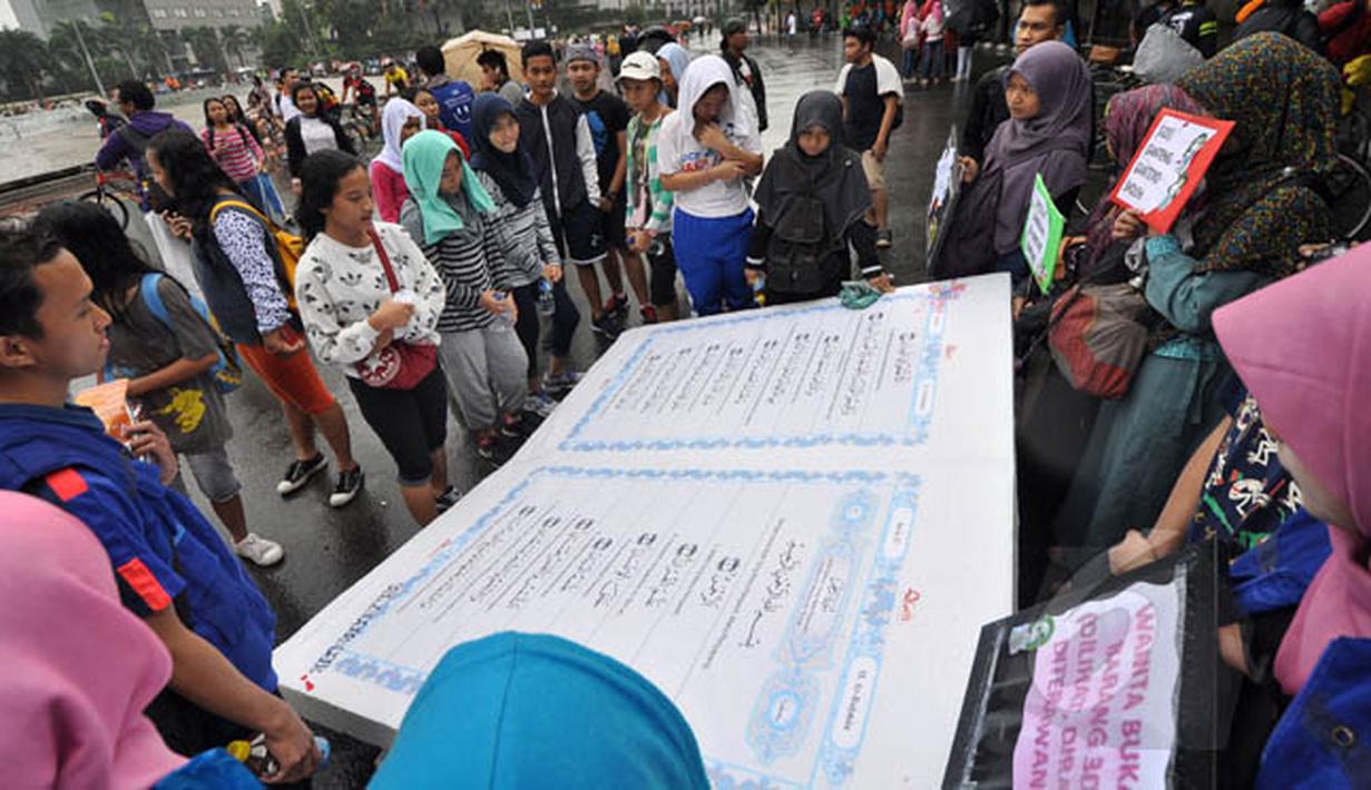 Sejumlah warga membaca Al-Quran raksasa saat Car Free Day di Bundaran HI, Jakarta, Minggu (8/2/2015). (Liputan6.com/Faizal Fanani)