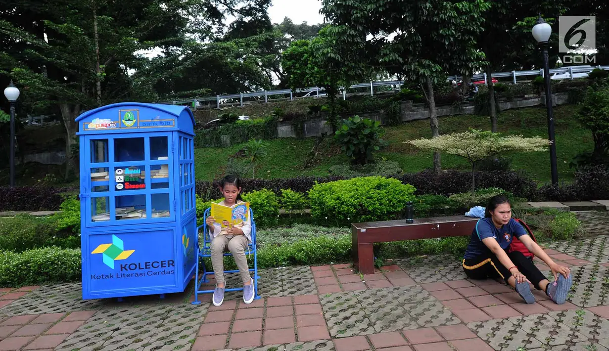 Warga berolahraga dekat anak yang sedang membaca buku di layanan Kotak Literasi Cerdas (Kolecer) di Taman Sempur, Bogor, Jawa Barat, Kamis (20/12). Kehadiran Kolecer bertujuan untuk menumbuhkan budaya literasi. (Merdeka.com/Arie Basuki)