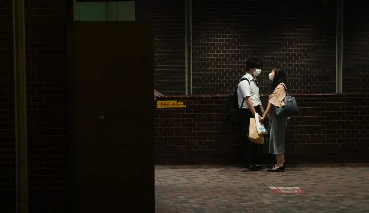 Pasangan berpegangan tangan di stasiun subway menjelang Olimpiade Musim Panas 2020 di Tokyo pada 14 Juli 2021. Di bawah protokol ketat, satu-satunya cara untuk melihat sekilas ibu kota adalah dari kendaraan yang mengantar para tamu dari perkampungan atlet atau hotel ke venue. (AP Photo/Jae C Hong)