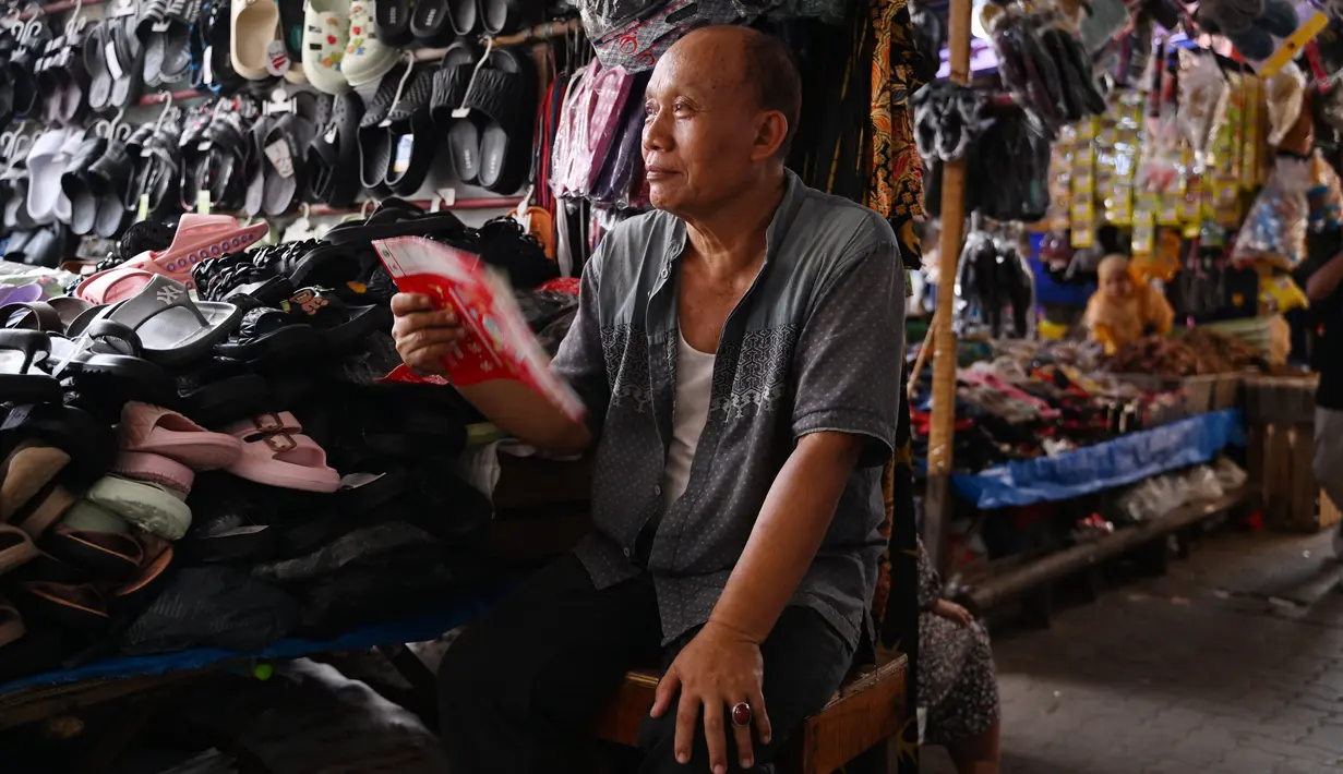 Seorang pedagang menggunakan selembar kertas untuk mendinginkan dirinya saat menunggu pelanggan di Jakarta pada 7 Mei 2024. (ADEK BERRY / AFP)
