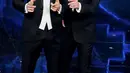 Striker AC Milan, Zlatan Ibrahimovic (kiri) dan presenter televisi Italia Amadeus tampil pada malam pembukaan festival musik San Remo di San Remo, Selasa (2/3/2021). Ibrahimovic yang sedang cedera melakukan debutnya sebagai pembawa acara di festival musik tersebut. (Marco RAVAGLI/AFP)
