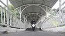 Pengendara sepeda motor melintasi jembatan penyeberangan orang (JPO) Stasiun Pasar Minggu Baru, Jakarta, Selasa (10/3/2020). JPO tersebut kerap disalahgunakan pengendara motor sebagai jalan alternatif untuk mempersingkat jarak tempuh meski rambu larangan sudah dipasang. (merdeka.com/Iqbal Nugroho)