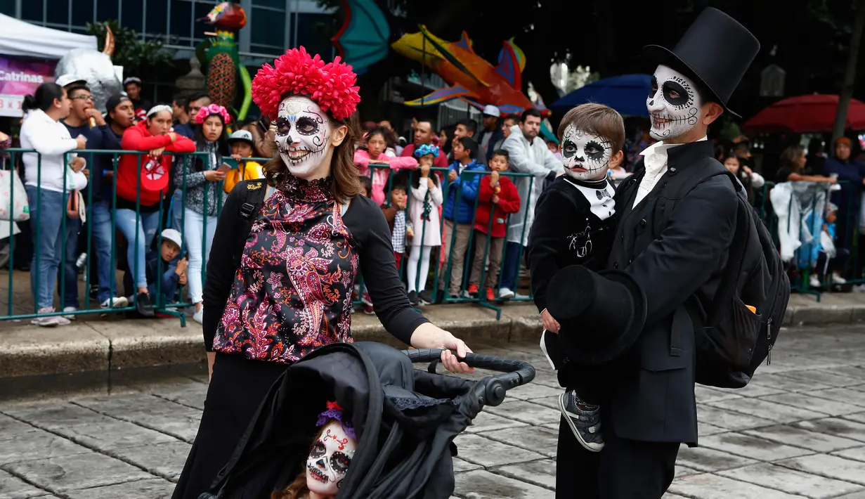 Sebuah keluarga berdandan ala tengkorak saat mengikuti parade Hari Orang Mati di Mexico City, Meksiko, Sabtu (26/10/2019. Para peserta dalam parade ini mengenakan kostum dan melukis wajah mirip dengan tokoh tengkorak Meksiko yang ikonik, Catrina. (AP Photo/Ginnette Riquelme)