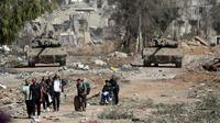 Warga Palestina melarikan diri ke Gaza utara saat tank-tank Israel memblokir jalan Salah al-Din di Jalur Gaza Tengah pada Jumat, 24 November 2023, saat gencatan senjata empat hari dalam perang Israel-Hamas dimulai sebagai bagian dari kesepakatan yang ditengahi oleh Qatar. (AP Photo/Mohammed Dahman)