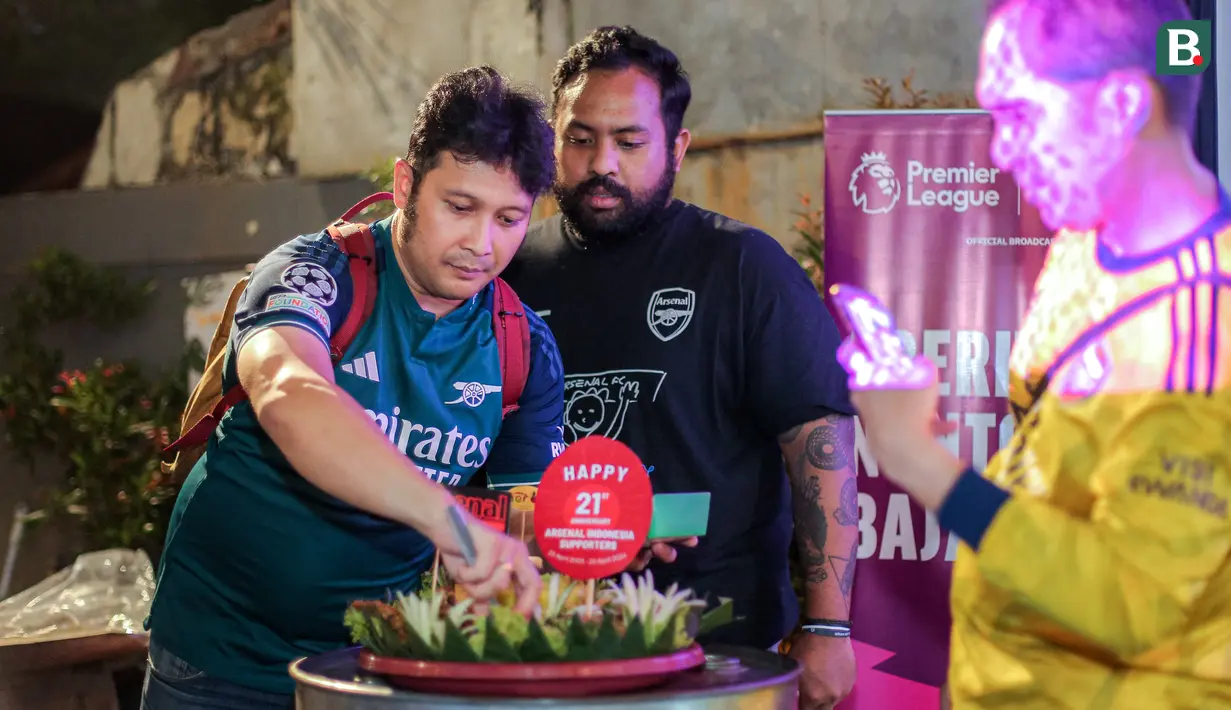 Ketua Arsenal Indonesia Supporters (AIS), Alif Sapto Nugroho (kiri) memotong nasi tumpeng untuk merayakan ulang tahun yang ke-21 AIS saat Roaring Night Liga Inggris antara Arsenal Vs Tottenham Hotspur di The Ground at Nipah, Jakarta Selatan, Minggu (28/04/2024). (Bola.com/Bagaskara Lazuardi)
