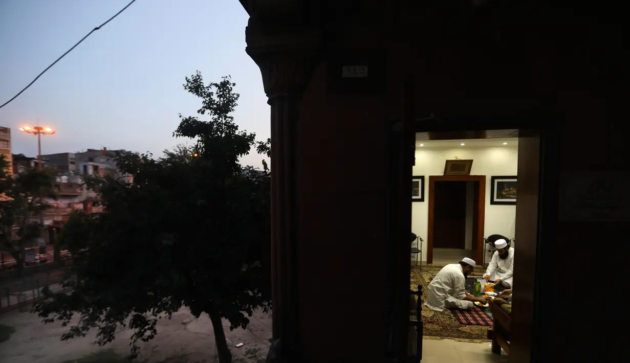 Umat Muslim berbuka puasa di Masjid Jama yang sepi, yang biasanya dipadati ribuan umat selama bulan suci Ramadan, karena penguncian nasional untuk mengendalikan penyebaran virus corona Covid-19, di New Delhi, India (25/4/2020). (AP Photo/Manish Swarup)
