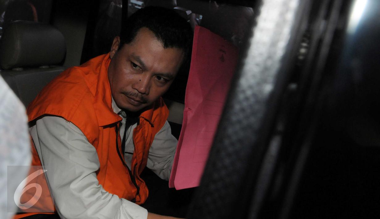 Dandung Pamularno menutupi wajahnya dengan map merah usai menjalani pemeriksaan KPK, Jakarta, Jumat (4/1). Dandung menjadi tersangka kasus penyuapan oknum di Kejati DKI Jakarta yang diamankan dalam operasi tangkap tangan. (Liputan6.com/Helmi Afandi)