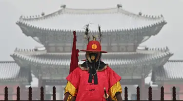 Seorang 'penjaga istana' berdiri untuk turis di depan Istana Gyeongbokgung yang tertutup salju di pusat kota Seoul (19/1/2022). Pihak berwenang di Seoul dan daerah sekitarnya pada Rabu (19/1) tetap waspada karena wilayah ibu kota diperkirakan akan turun salju lebat sepanjang hari. (AFP/Jung Yeon-je)