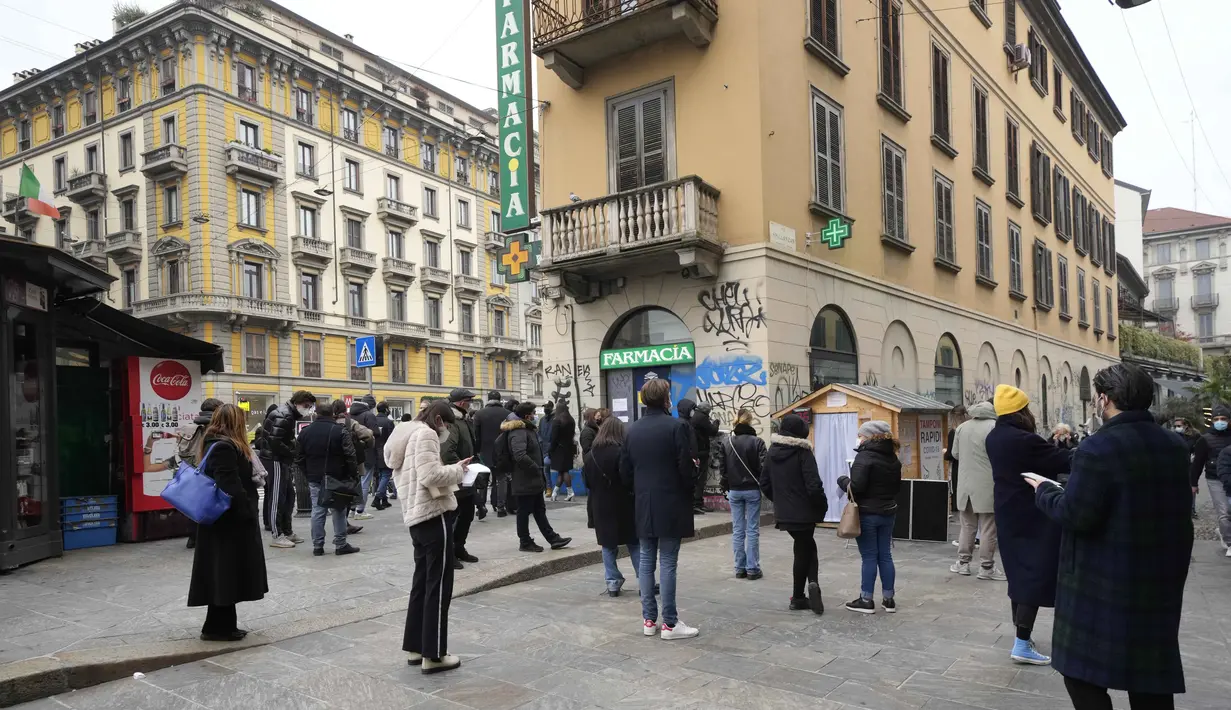Orang-orang berbaris di situs pengujian COVID-19 mobile di sebelah apotek di Milan, Italia, Selasa (21/12/2021). Negara-negara di seluruh Eropa mempertimbangkan pembatasan yang lebih ketat guna membendung gelombang baru infeksi COVID-19 yang didorong oleh varian omicron. (AP Photo/Luca Bruno)