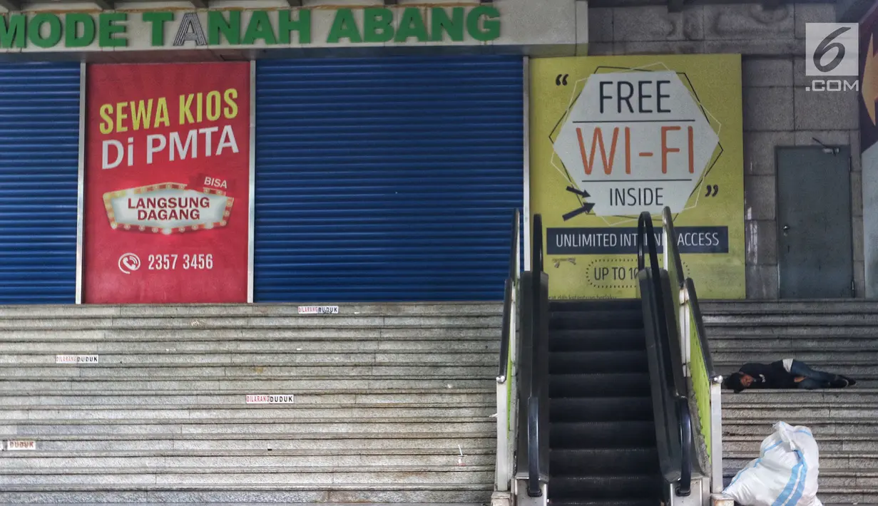 Seorang pria tidur di tangga Blok A Tanah Abang, Jakarta, pada hari ketiga Lebaran, Jumat (7/6/2019). Selepas Hari Raya Idul Fitri, Pasar Tanah Abang masih tutup dan direncanakan buka pada Kamis (13/6) mendatang. (Liputan6.com/Johan Tallo)