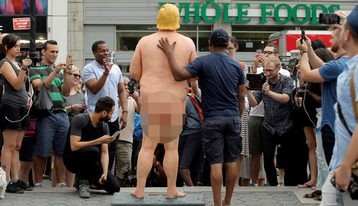 Sejumlah warga memfoto patung Donald Trump tanpa busana yang dipajang di Union Square Park, AS, Kamis (18/8). Warga di sekitar Union Square Park, New York, rela mengantre untuk berfoto dengan patung tersebut. (REUTERS/Brendan McDermid)