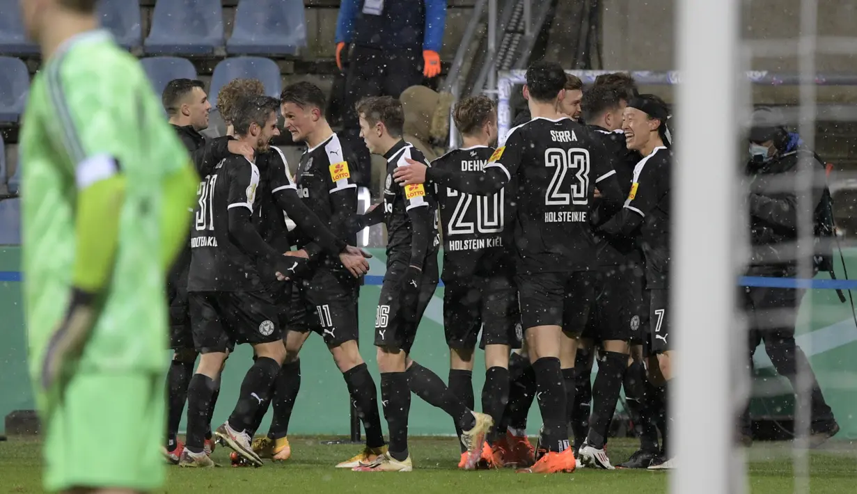 Para pemain tim Divisi 2 Holstein Kiel merayakan gol penyeimbang 2-2 ke gawang Bayern Munich dalam laga babak kedua Piala DFB Pokal 2020/21 di Kiel, Rabu (13/1/2021). Holstein Kiel menang atas Bayern Munich lewat adu penalti 5-6 (2-2). (AFP/Fabian Bimmer/Pool)