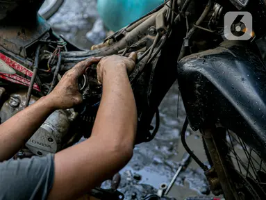 Montir memperbaiki sepeda motor konsumen usai terendam banjir di kawasan Mampang, Jakarta, Minggu (21/2/2021). Banjir yang melanda Ibu Kota Jakarta pada Sabtu (20/2) menyebabkan banyak kendaraan warga mengalami kerusakan akibat terendam air. (Liputan6.com/Faizal Fanani)