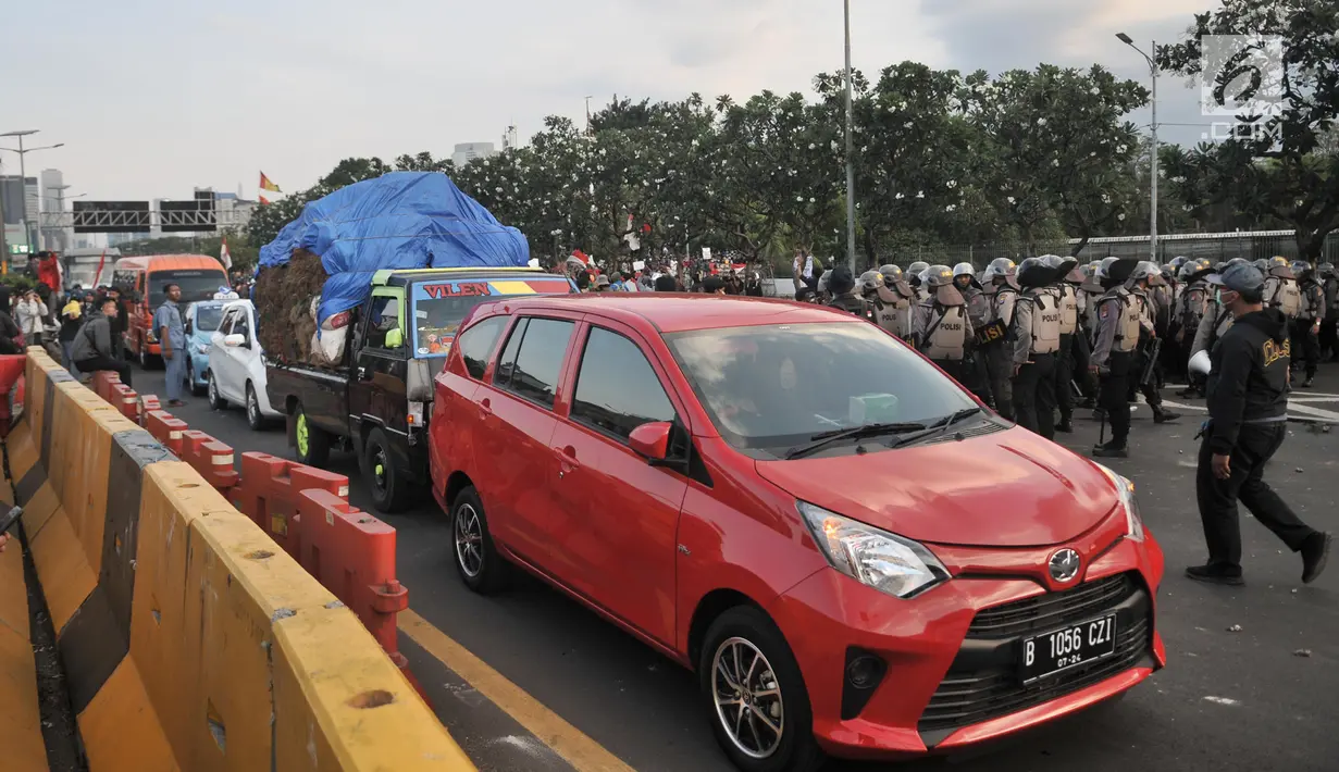 Sejumlah kendaraan berusaha melintas di antara massa pengunjuk rasa yang memasuki Tol Dalam Kota dekat Gedung DPR,  Jakarta, Senin (30/9/2019). Kendaraan yang melintasi terjebak bentrokan antara massa dan polisi yang terjadi di dua sisi sehingga terpaksa berputar arah. (merdeka.com/Iqbal S Nugroho)