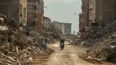 Seorang pria mengendarai sepeda motor melewati puing-puing bangunan yang hancur di Samandag, Turki selatan, Rabu, 22 Februari 2023. Korban selamat gempa bumi yang mengguncang Turki dan Suriah 15 hari lalu, menewaskan puluhan ribu orang dan meninggalkan ratusan ribu lainnya tunawisma, menghadapi lebih banyak trauma dan kehilangan setelah gempa mematikan dan gempa susulan mengguncang wilayah tersebut. (AP Photo/Emrah Gurel)