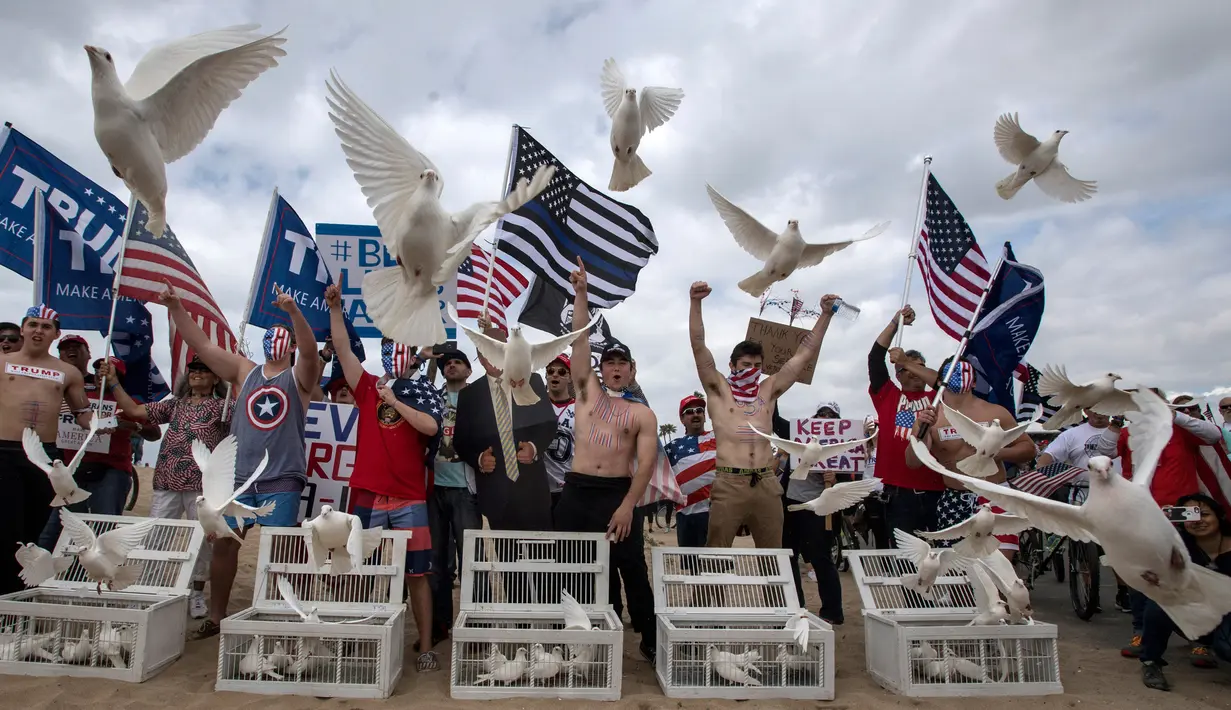 Pendukung Presiden Donald Trump melepaskan merpati selama pawai di Huntington Beach, California (25/3). Keributan kemudian pecah di pantai Southern California antarapendukung Trump dan anti-Trump. (Mindy Schauer / The Orange County Register via AP)