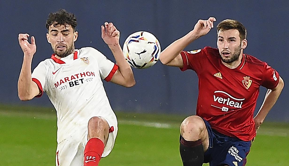 Striker Sevilla, Munir El Haddadi (kiri) berebut bola dengan gelandang Osasuna, Alejandro Pozo dalam laga lanjutan Liga Spanyol 2020/21 pekan ke-24 di El Sadar Stadium, Plampona, Senin (22/2/2021). Sevilla menang 2-0 atas Osasuna. (AFP/Ander Gillenea)